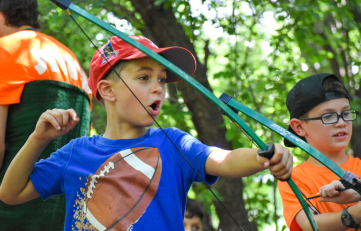 A boy shooting with a bow and arrow.