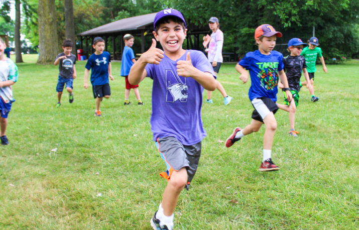 A boy running and giving a thumbs up.