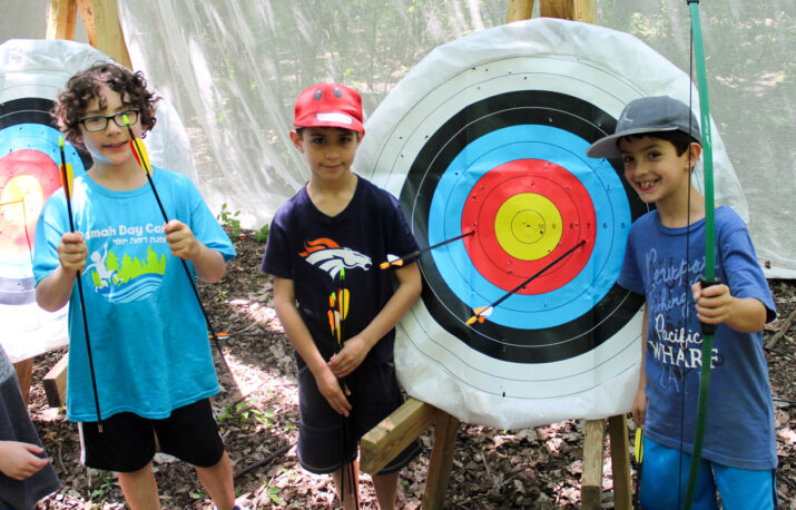 Boys standing in front of a archery bullseye.