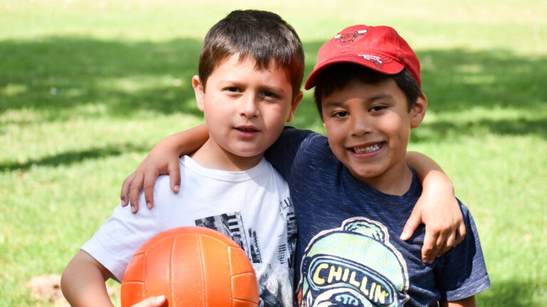 Two children embracing and smiling at the camera.