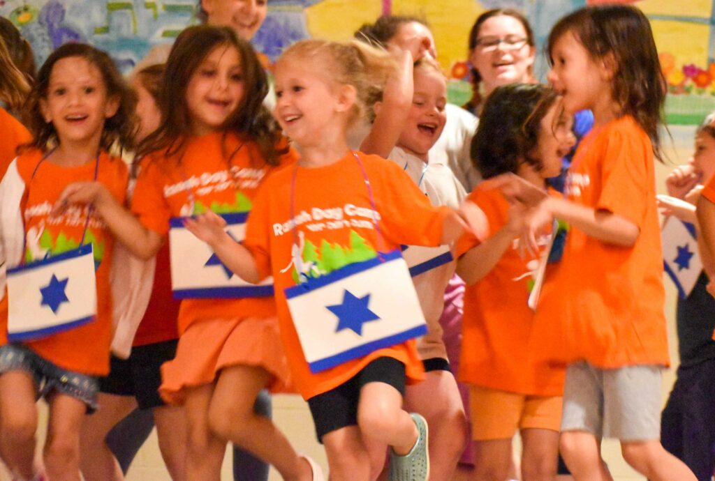 Children running around in orange tee shirts.