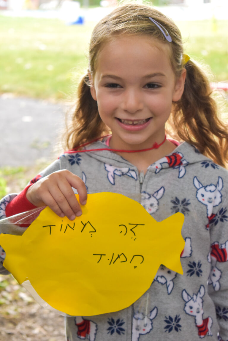 A girl holding a card with hebrew writing.