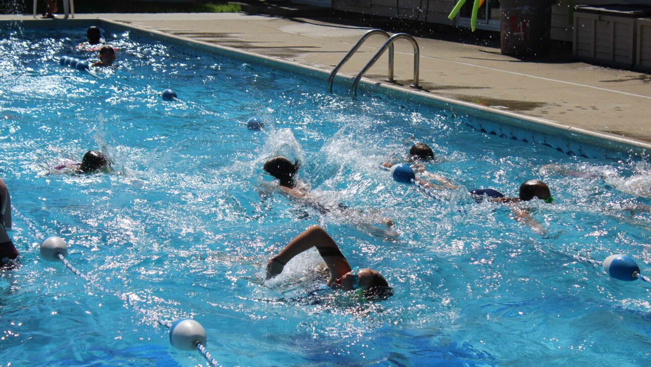 Campers swimming in an outdoor pool.