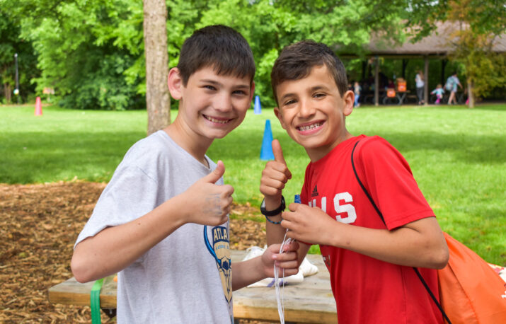 Two boys giving a thumbs up to the camera.