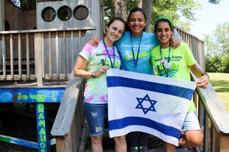 Three teens embracing and smiling at the camera.